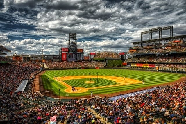 A Major League Baseball stadium buzzes with excitement as spectators fill the seats under a cloudy sky, eagerly watching the players on the field.