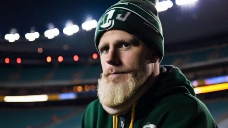A person in a green and white hat and hoodie stands in a stadium at night, pondering CFL rules as the game unfolds.