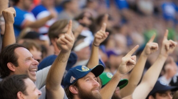 Crowd of sports fans in a stadium, wearing team jerseys and hats, cheer enthusiastically with their arms raised, creating an electrifying Battle of the Fans atmosphere.