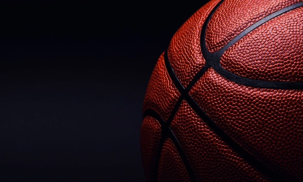 Close-up of a basketball on a dark background, evoking the classic feel of 90s basketball with its textured surface and black seams, reminiscent of the iconic NBA era.