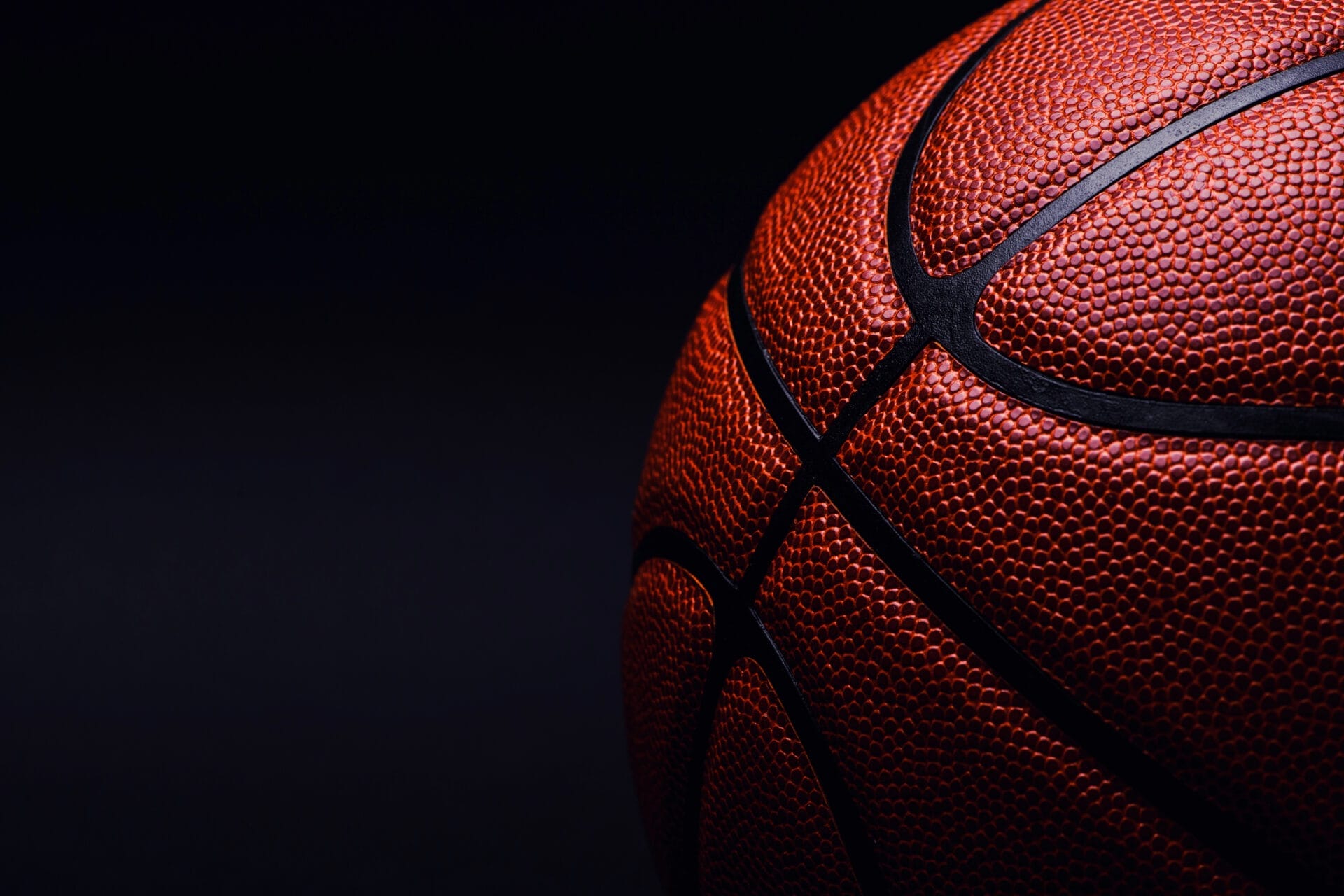 Close-up of a basketball on a dark background, evoking the classic feel of 90s basketball with its textured surface and black seams, reminiscent of the iconic NBA era.