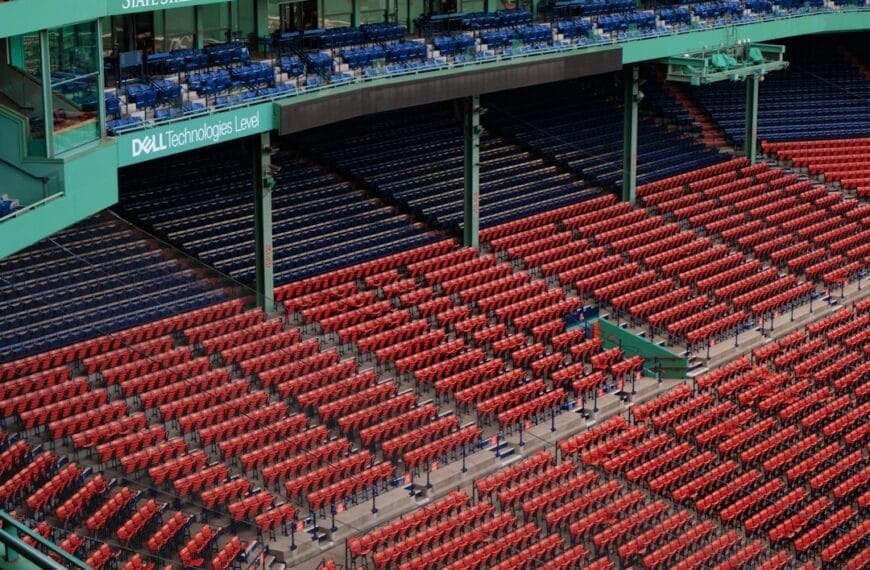 A view of a stadium's seating area reveals rows of red seats in the lower section and blue seats above. Dell Technologies' branding stands out on the green structure, a subtle backdrop amid discussions of MLB rule changes sweeping through the baseball community.