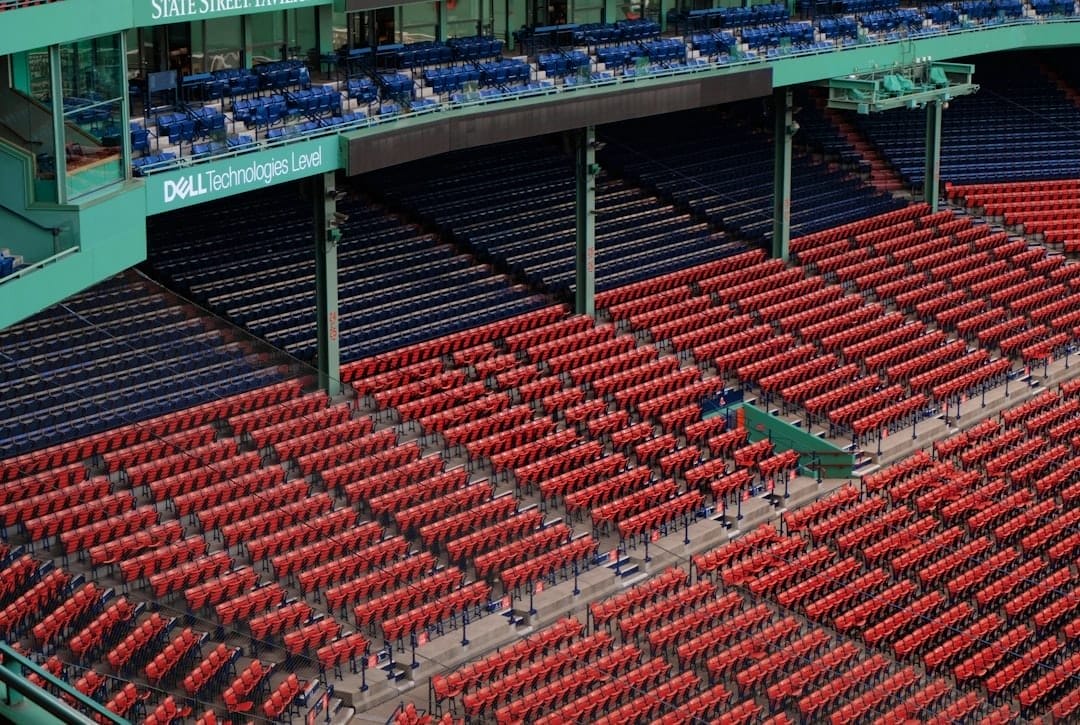 A view of a stadium's seating area reveals rows of red seats in the lower section and blue seats above. Dell Technologies' branding stands out on the green structure, a subtle backdrop amid discussions of MLB rule changes sweeping through the baseball community.