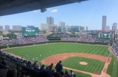 View of a baseball game at a stadium with a city skyline in the background, where fans eagerly discuss an MLB rule change that has added fresh excitement to the season.