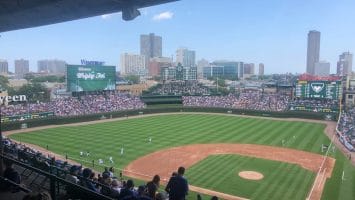 View of a baseball game at a stadium with a city skyline in the background, where fans eagerly discuss an MLB rule change that has added fresh excitement to the season.