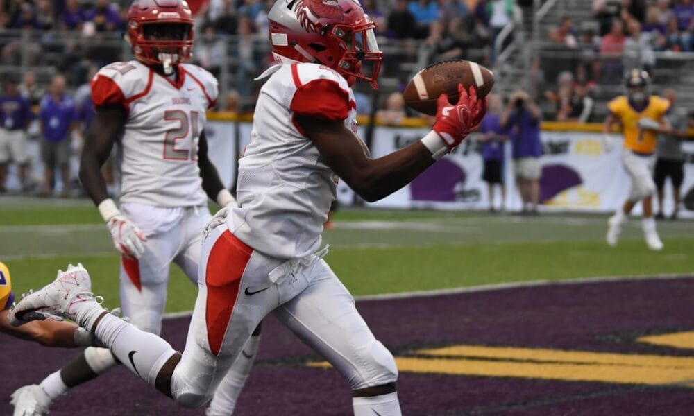 A football player in a white uniform catches a pass in the end zone as machine learning in sports revolutionizes strategies; teammates and the crowd cheer in the background.