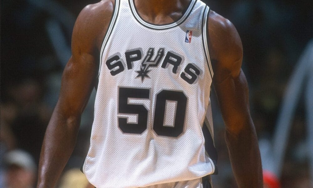 Basketball player in a Spurs jersey numbered 50, reminiscent of NBA legend David Robinson, standing on a court.