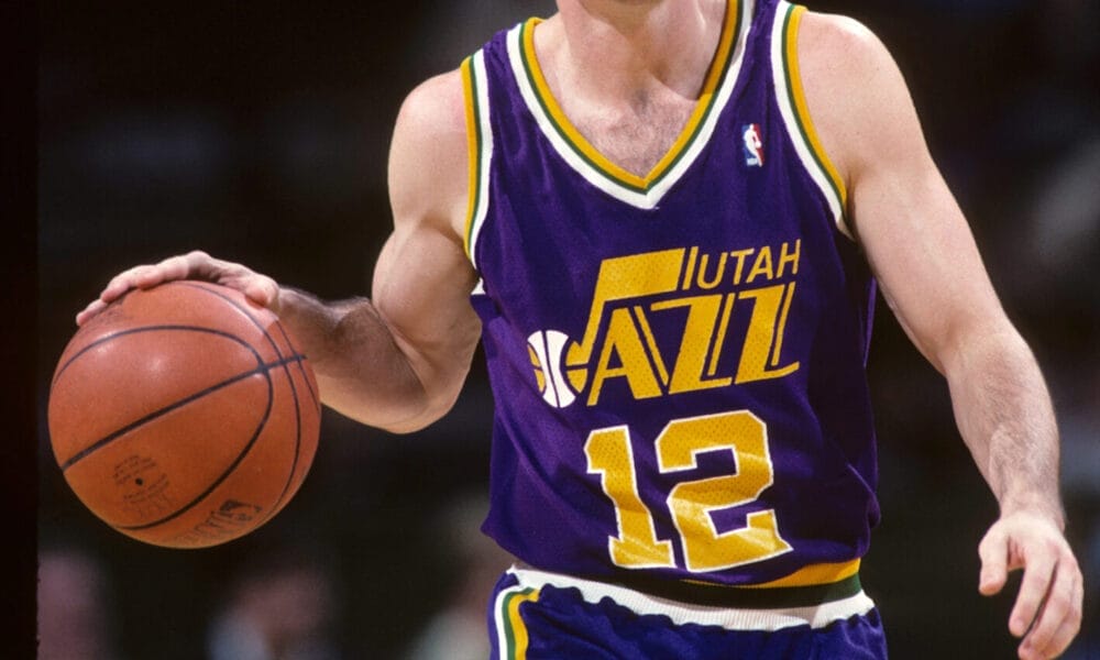 NBA legend John Stockton, in a purple Utah Jazz uniform, skillfully dribbles the ball down the court.