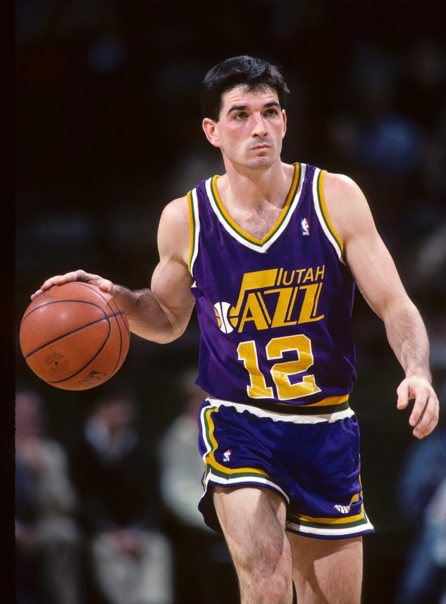 NBA legend John Stockton, in a purple Utah Jazz uniform, skillfully dribbles the ball down the court.