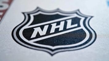 Close-up of the black and white NHL (National Hockey League) shield logo printed on a textured white surface. The bold "NHL" letters, paired with advanced NHL analytics, symbolize the league’s forward-thinking approach to the game.